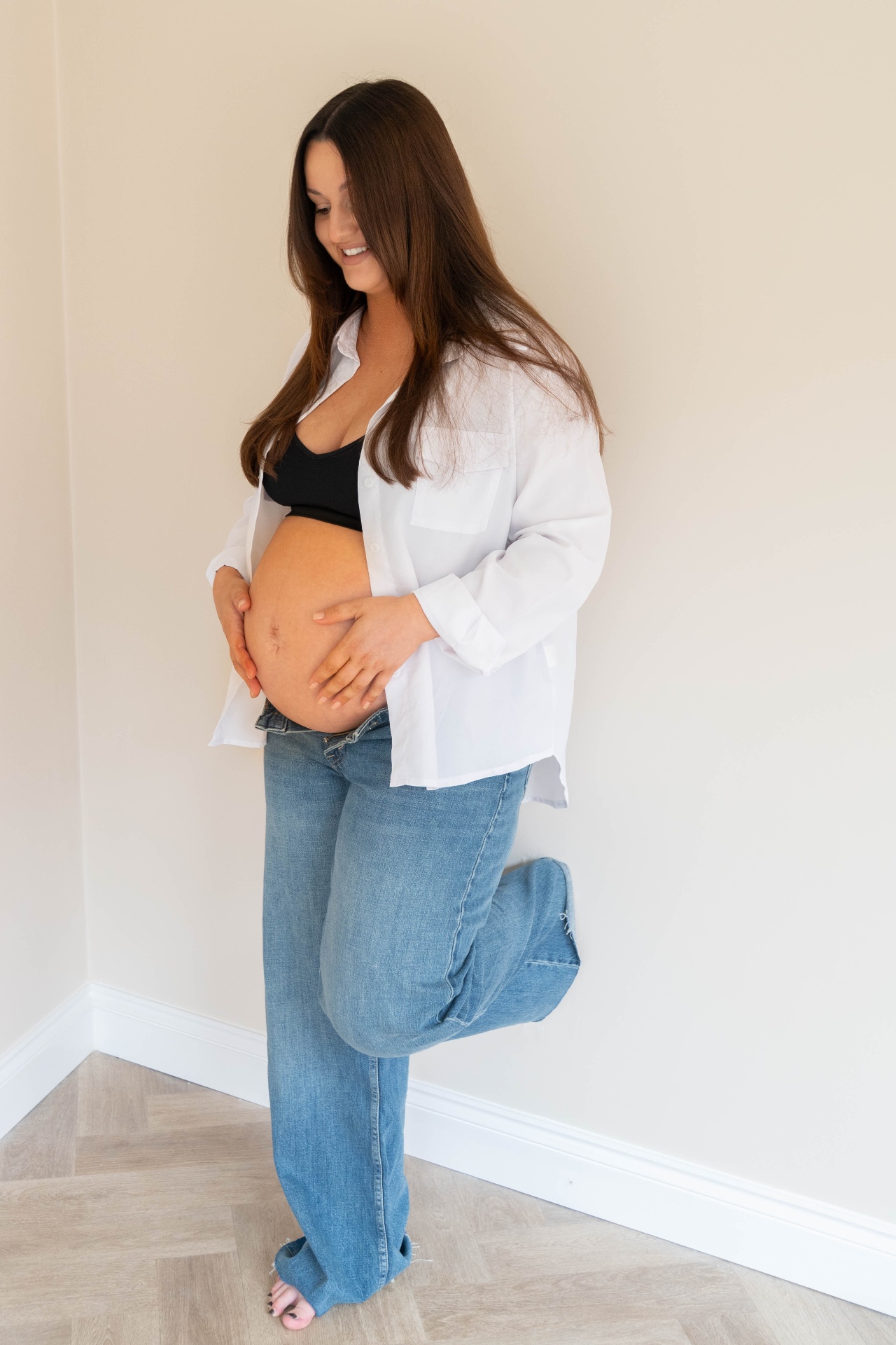 Full length maternity portrait against a warm neutral wall