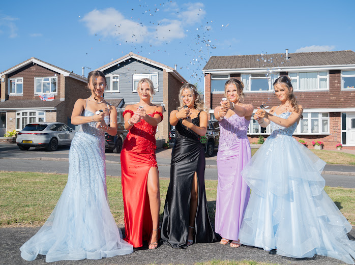 Five friends firing confetti cannons before prom