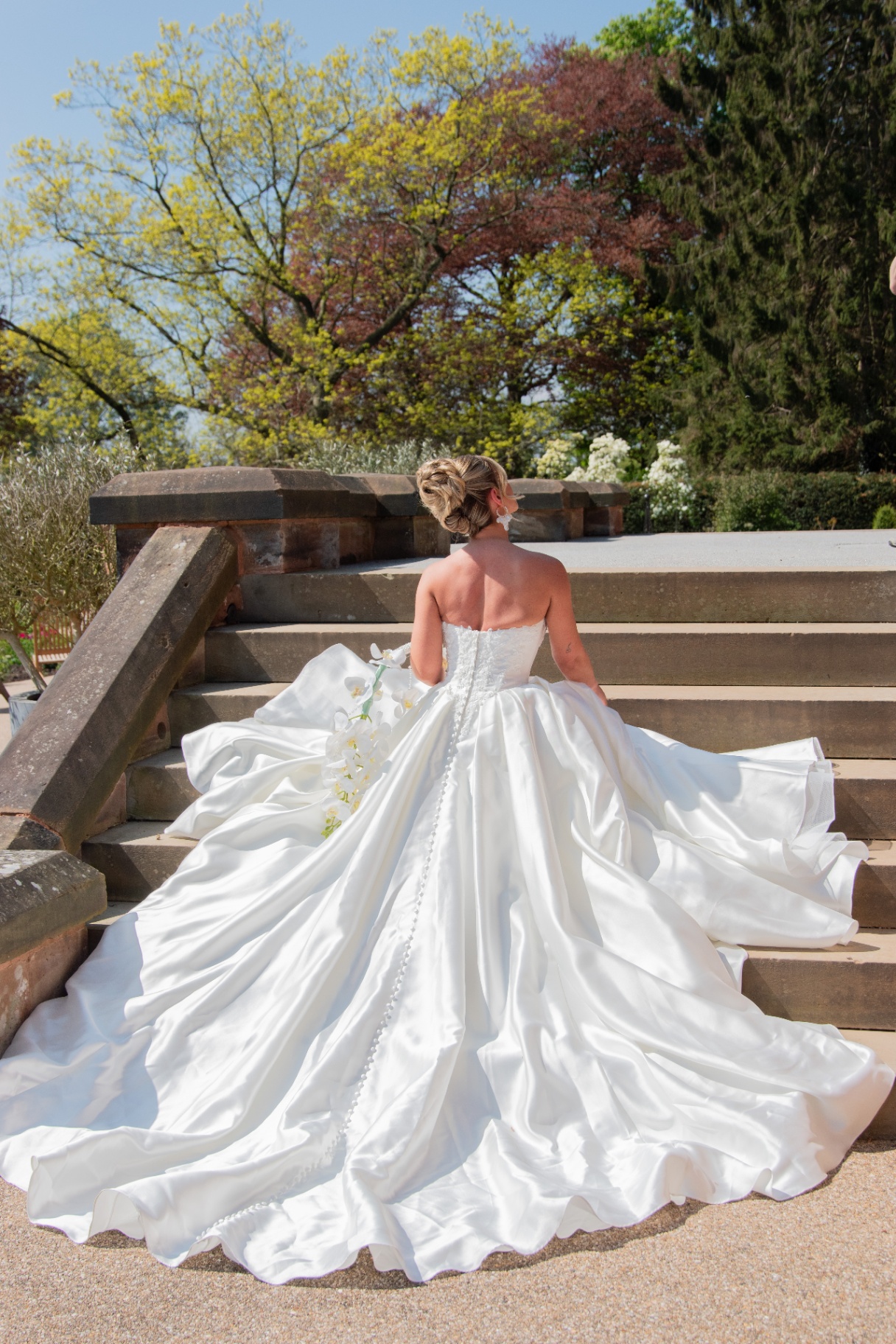 Bride on stone steps with a sweeping satin gown