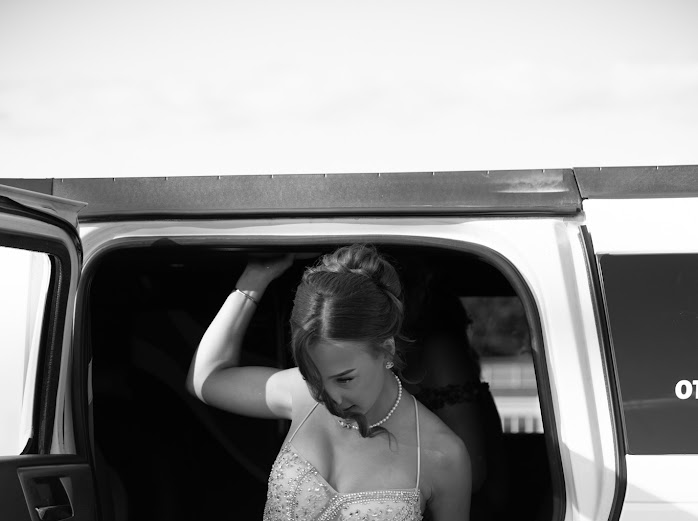 Black and white portrait of a girl stepping out of a limousine on prom night