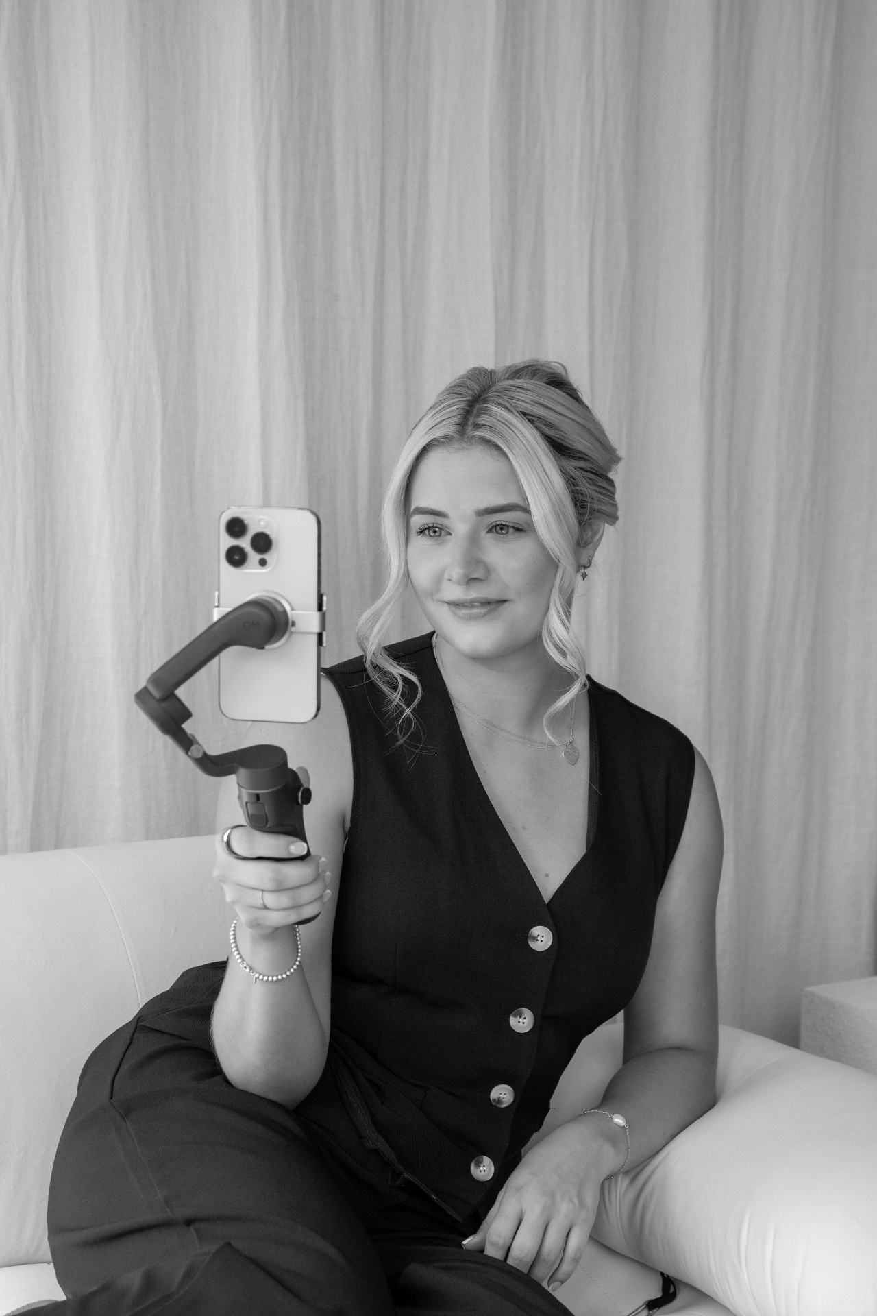 Content creator filming with a gimbal on a cream sofa