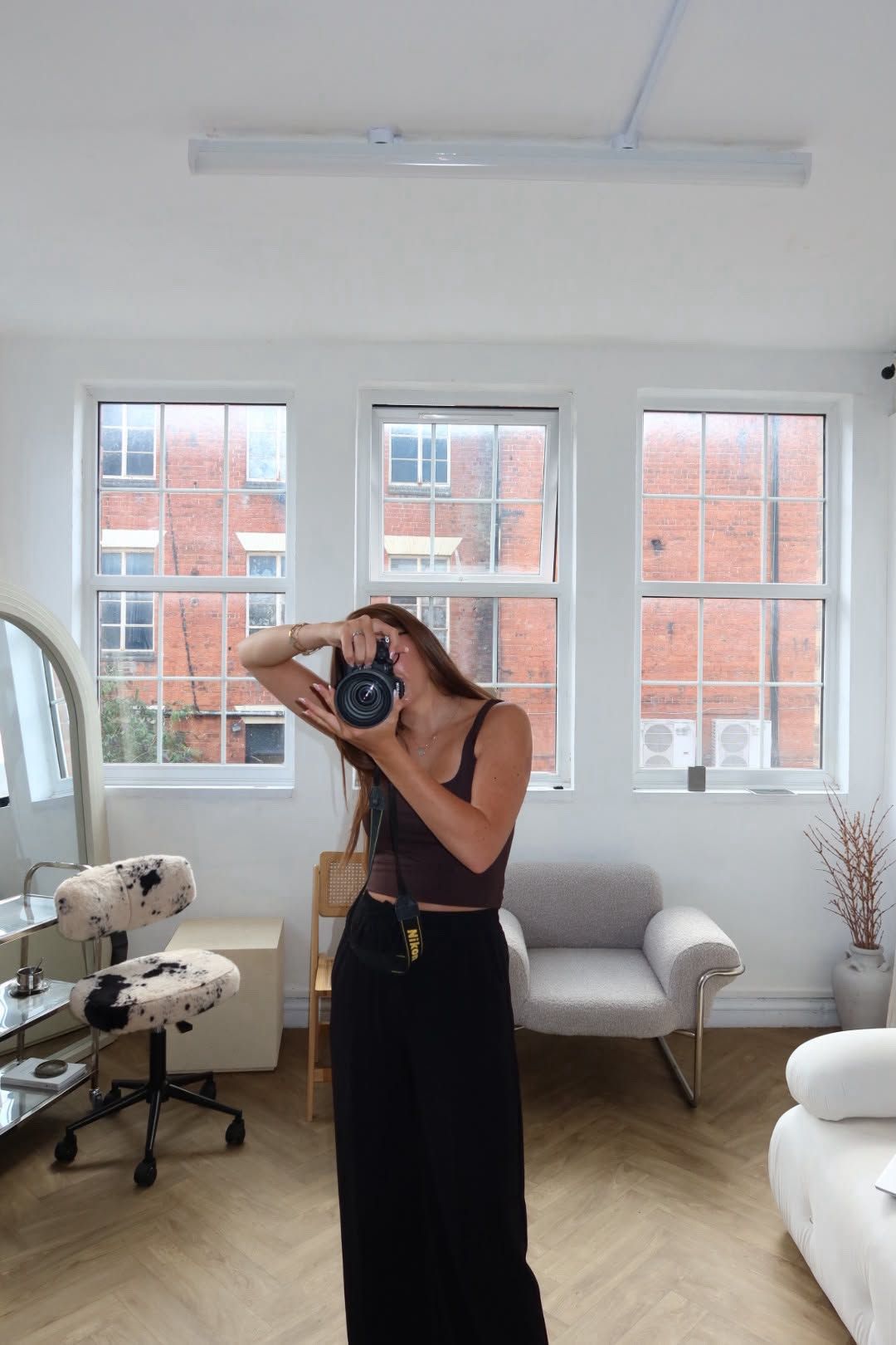Imogen, photographer, holding a camera by a window