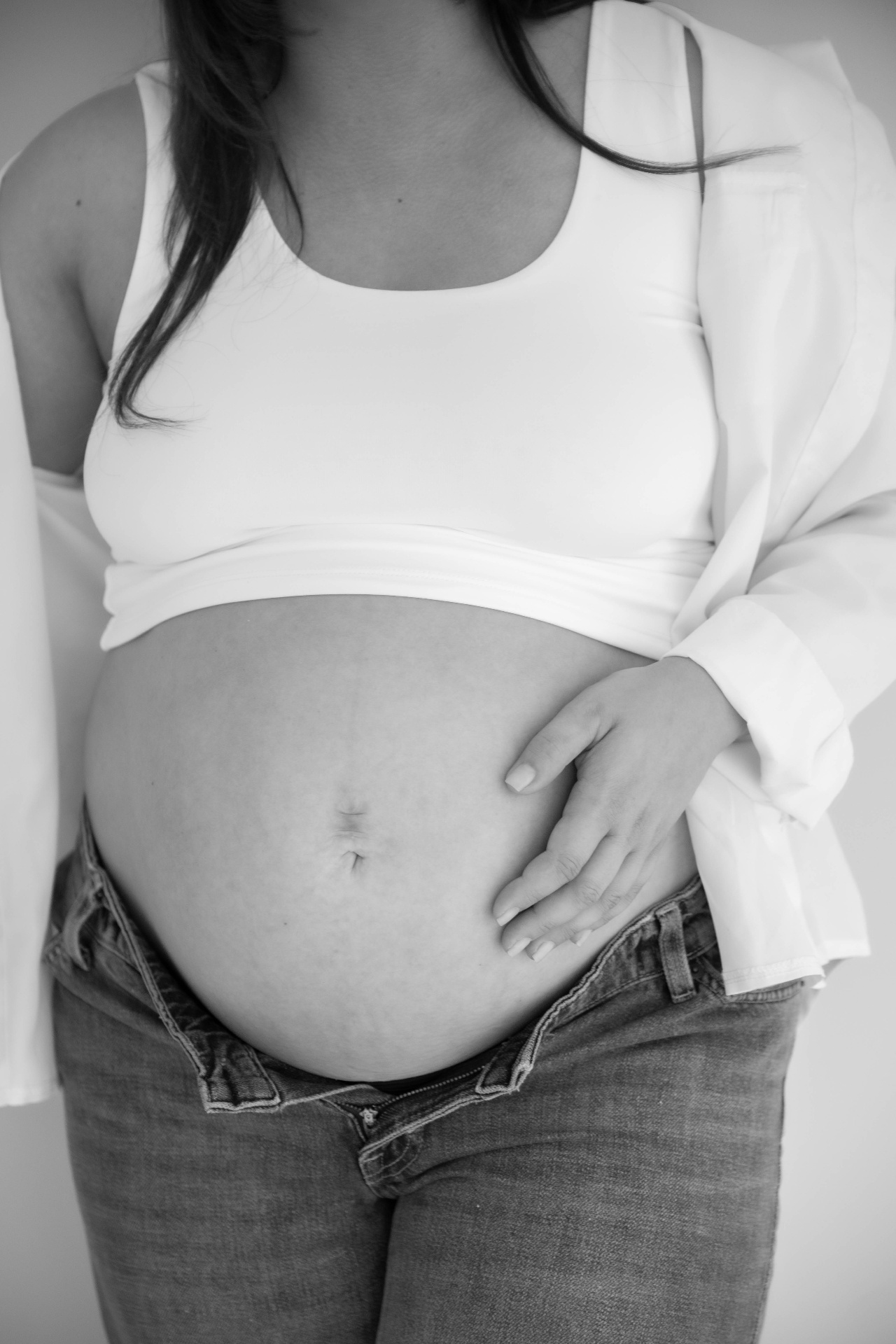 Black and white close detail of a bump in a white top and denim