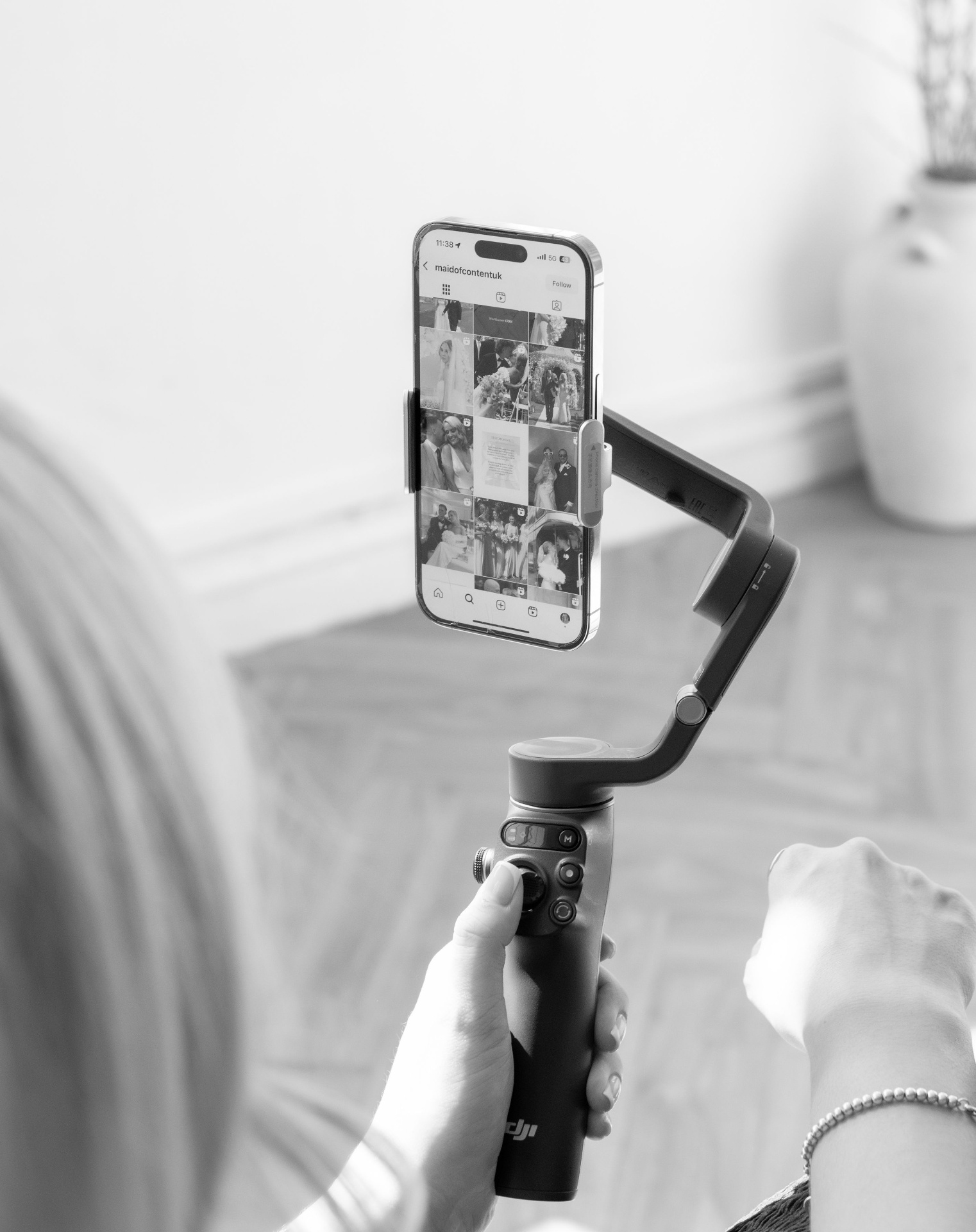 Black and white detail of a phone on a gimbal showing an Instagram feed